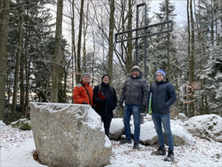 Vier Personen stehen vor dem Gipfelkreuz auf dem Freyunger Geyersberg 